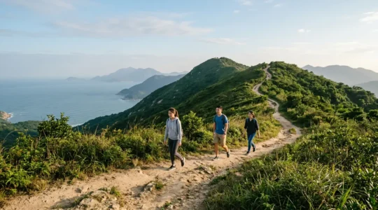 Hikers in casual sneakers walking along Dragon's Back ridge trail with panoramic coastal views and clear blue sky