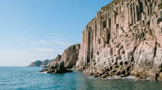 Dramatic coastal view of towering hexagonal volcanic rock columns rising from turquoise waters in Hong Kong UNESCO Global Geopark