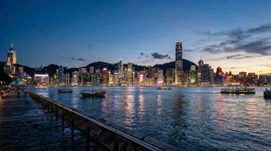 Hong Kong skyline at dusk with modern skyscrapers reflecting in Victoria Harbour, representing connectivity and travel preparation