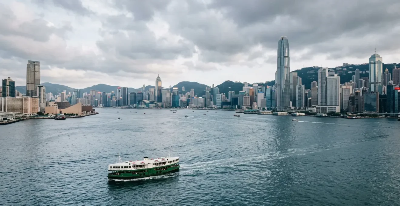 Iconic green and white Star Ferry crossing Victoria Harbour with Hong Kong's dramatic skyline in the background