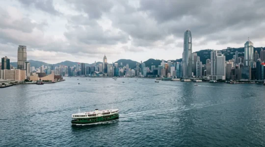 Iconic green and white Star Ferry crossing Victoria Harbour with Hong Kong's dramatic skyline in the background