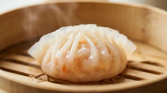 Close-up of a perfectly steamed har gow shrimp dumpling showing translucent skin and visible pink shrimp filling