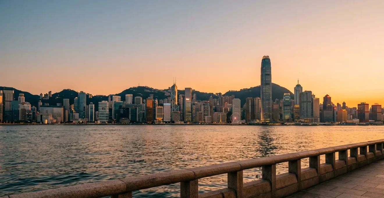 Golden hour view of Victoria Harbour from Tsim Sha Tsui waterfront with Hong Kong Island skyline reflecting on calm waters
