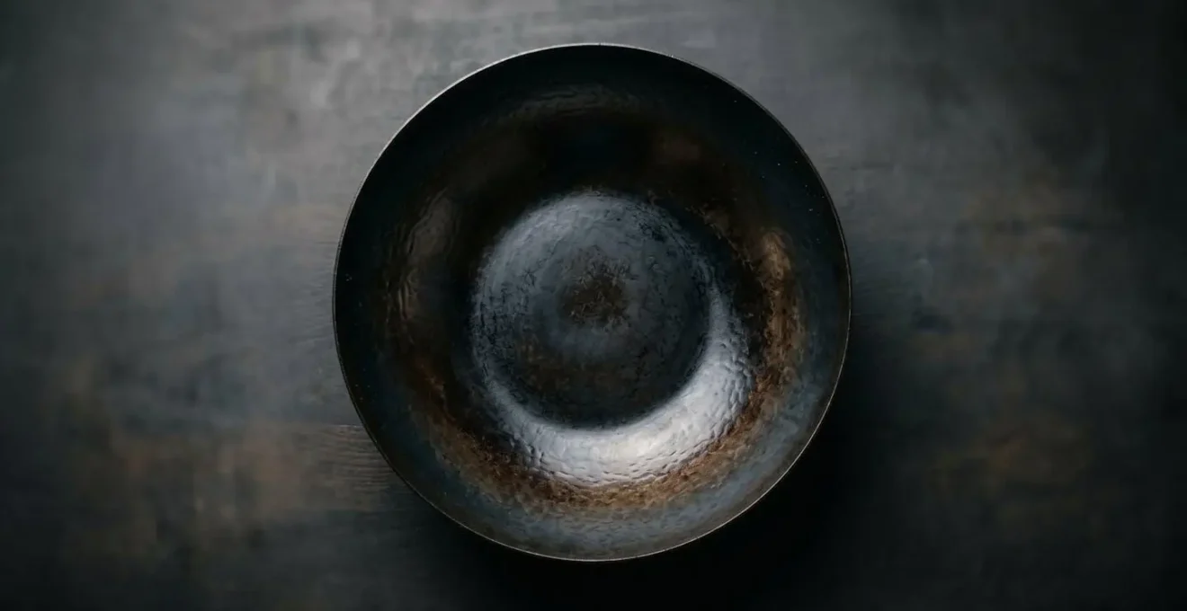 Well-seasoned carbon steel wok photographed from above showing the dark patina and curved interior surface