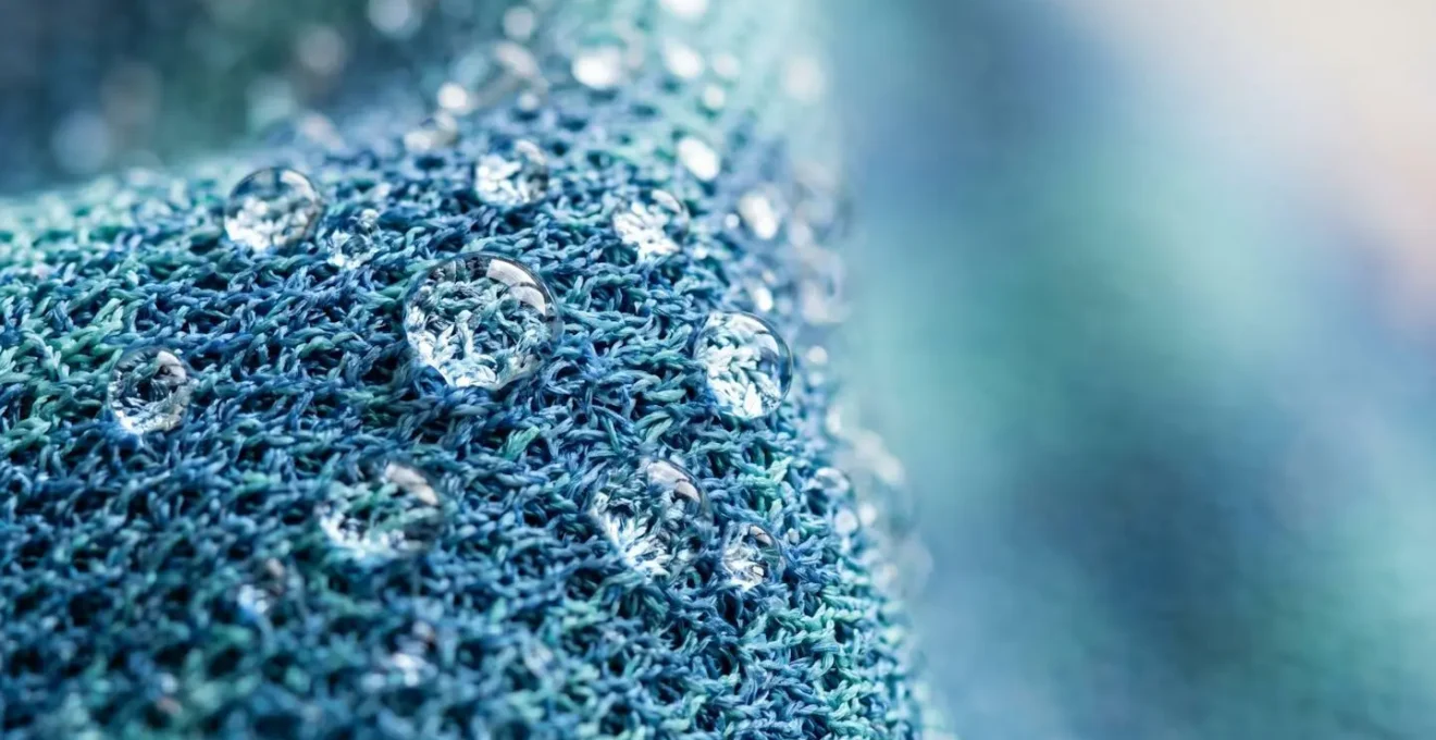 Extreme close-up of water droplets on evaporative cooling towel fabric showing moisture-wicking texture