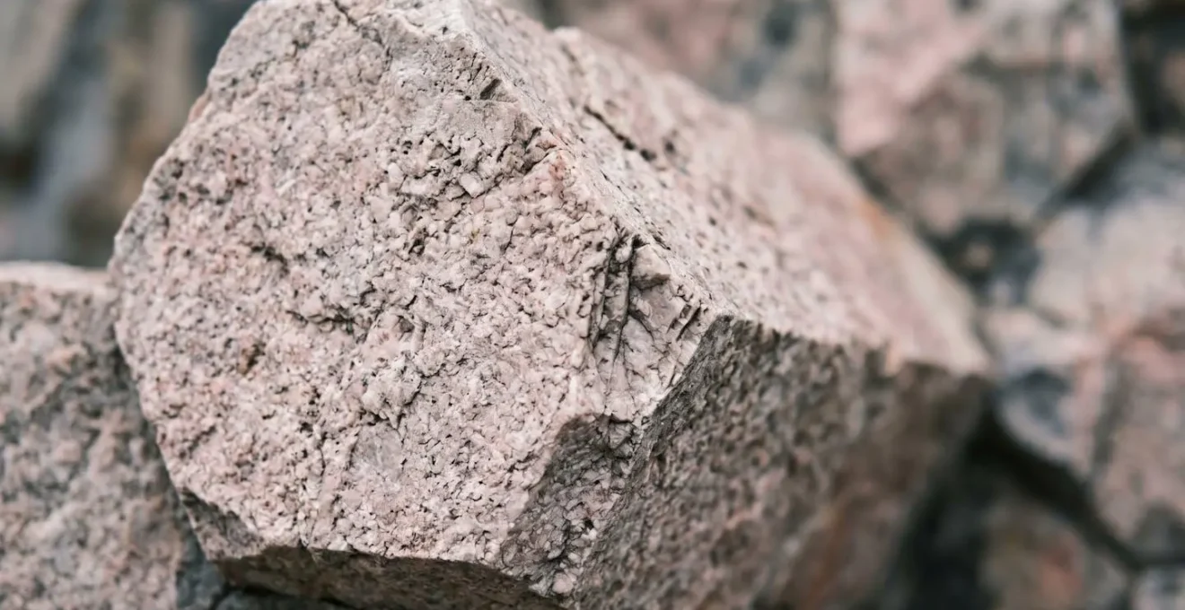 Extreme close-up of light pinkish-grey rhyolitic hexagonal rock column surface showing fine-grained texture and geometric jointing pattern