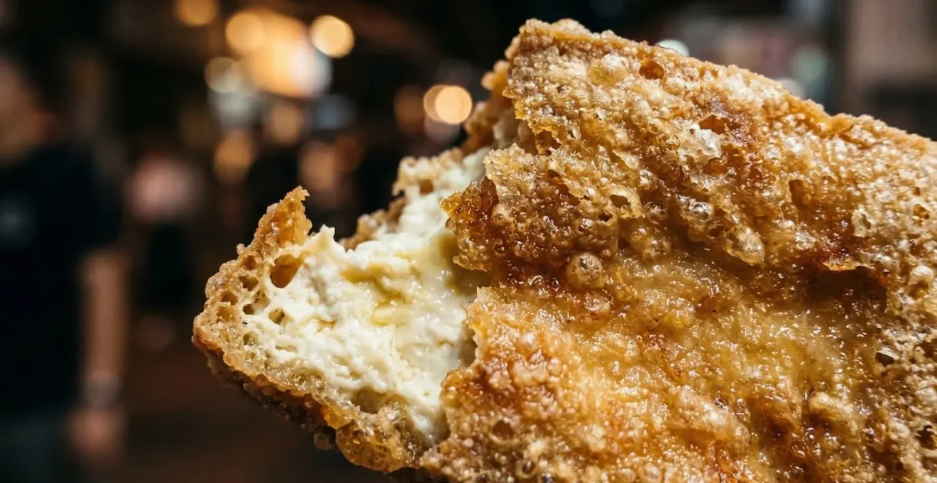 Extreme close-up of crispy golden fried stinky tofu texture showing the contrast between crispy exterior and soft interior